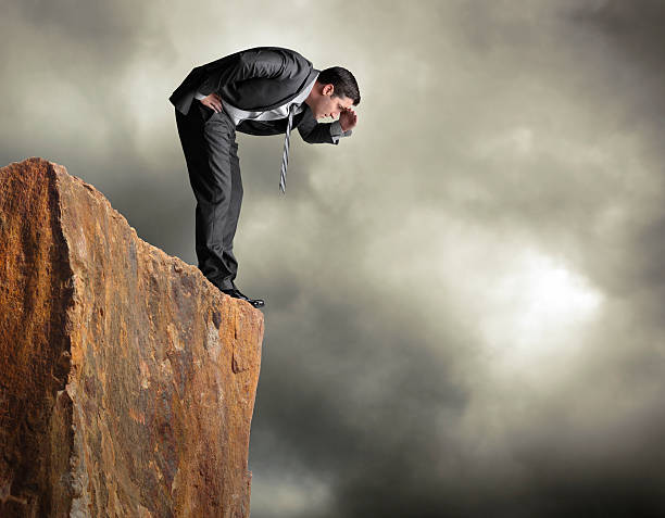 istock Businessman standing on edge of cliff looking down 174084965