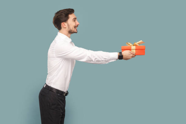 istock Side view portrait of friendly positive optimistic man with mustache giving red present box. 1740855281