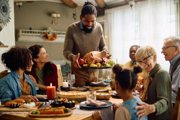 istock Happy black man serving Thanksgiving turkey to his extended family at dining table. 1740856447