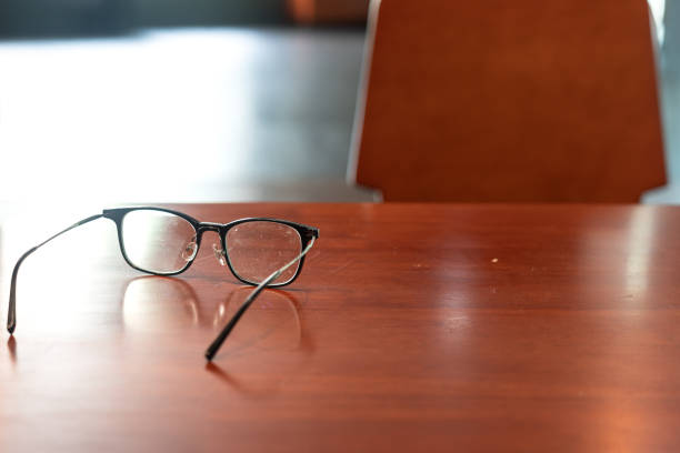 A classic design eyeglasses is placed on the wooden table. Resting from stress business working concept scene. Close-up at object and selective focus.
