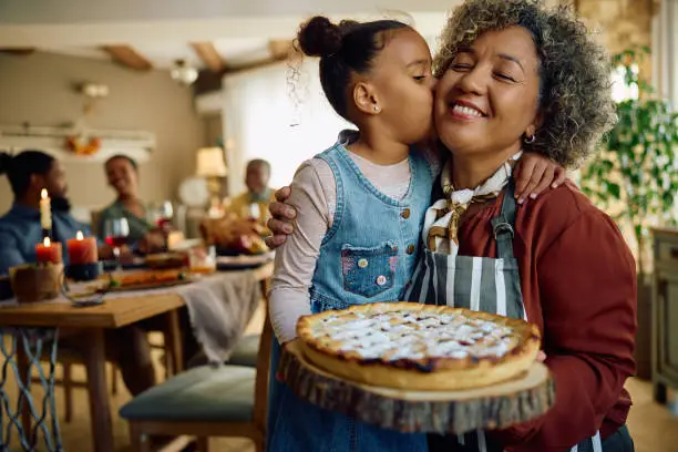 Photo of Affectionate grandmother and granddaughter with freshly baked holiday pie.