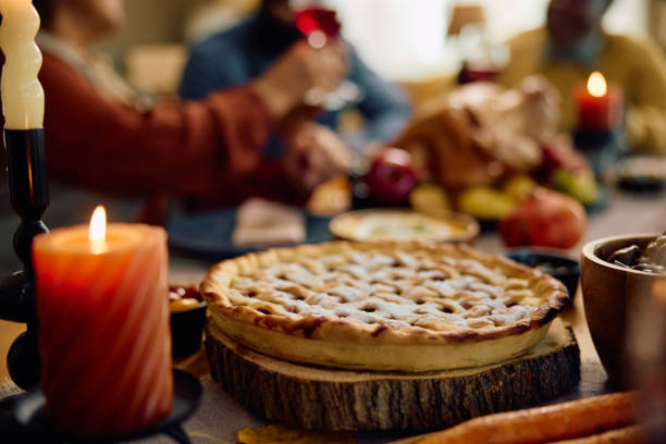 istock Thanksgiving pie on dining table with family in the background. 1740861676