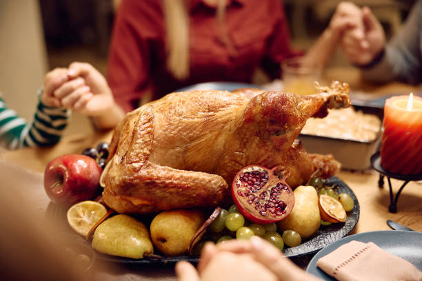 istock Thanksgiving turkey with family saying grace at dining table. 1740863709