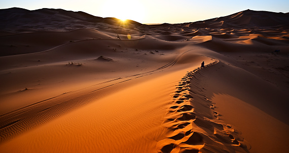 admire the sun rising at dawn from behind the sand dune in the heart of the Sahara desert