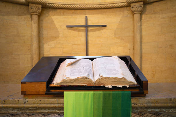 Open Bible on wooden background, Holy book of Christianity. Cross on the wall.