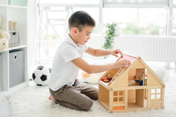 istock Cute little boy playing with dollhouse 1740890703