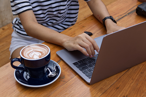 Women using laptop working and drinking coffee cup hot in the morning background