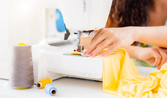 Close up view of female hands working on sewing machine