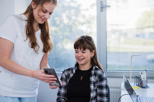 Nurse and a young patient excitedly explore a medical app on a smartphone, their faces filled with curiosity and enthusiasm