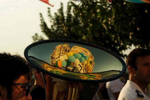 On September 1, 2023, during the opening procession of the Izmir International Fair, a musician played the tuba. A close-up of the instrument reveals a reflection of the city's buildings and floating balloons, merging music with the vibrant atmosphere of the event