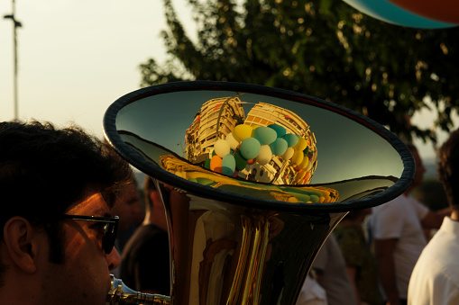 On September 1, 2023, during the opening procession of the Izmir International Fair, a musician played the tuba. A close-up of the instrument reveals a reflection of the city's buildings and floating balloons, merging music with the vibrant atmosphere of the event