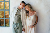 Couple in love standing near the wall. A pregnant woman holds her husband's hand.