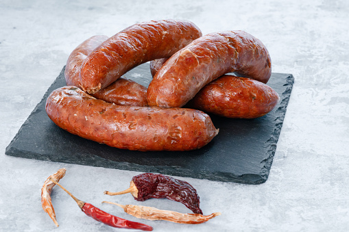 fresh raw bratwurst sausages Merguez with salt and chili peppers on wood board