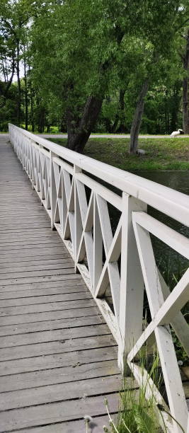 Wooden white footbridge over the river in a park. stock photo
