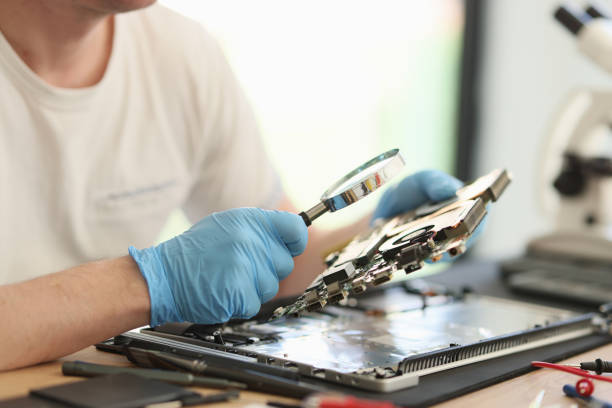 istock Man looks at printed circuit board through magnifier glass 1740942209