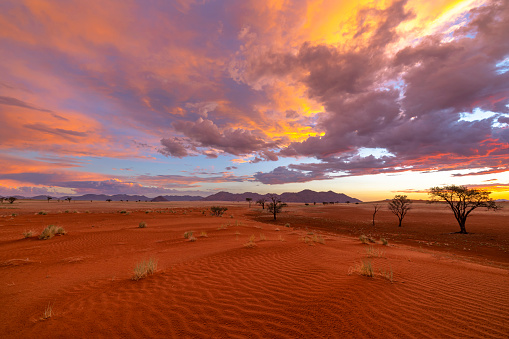 Red sand under red and yellow clouds Namibia