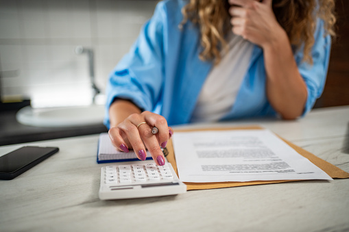 A young woman at home calculates the balance of her financial plans and checks the letter she received with the bank statement