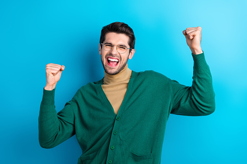 Photo of satisfied delighted person raise fists luck attainment shout yeah isolated on blue color background.