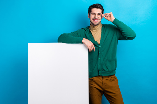 Photo of young librarian worker wear green cardigan casual outfit touch specs hand over placard mockup isolated on blue color background.