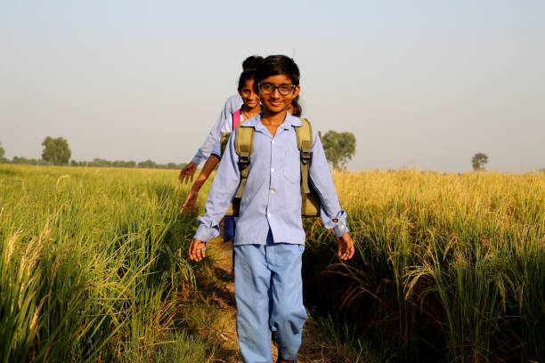 des élèves d’âge primaire marchent sur une route de campagne après l’école - developing countries farmer rice paddy asia photos et images de collection
