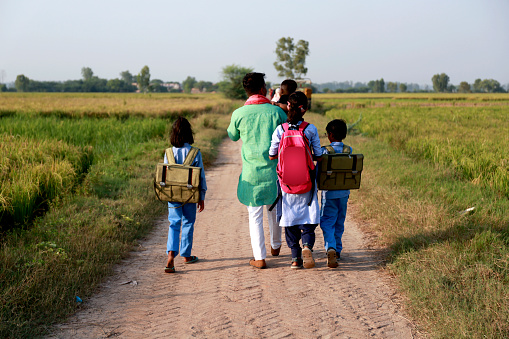 Farmer family walking on country road near green field after school vacation wearing school uniform portrait close up outdoor in nature during springtime.