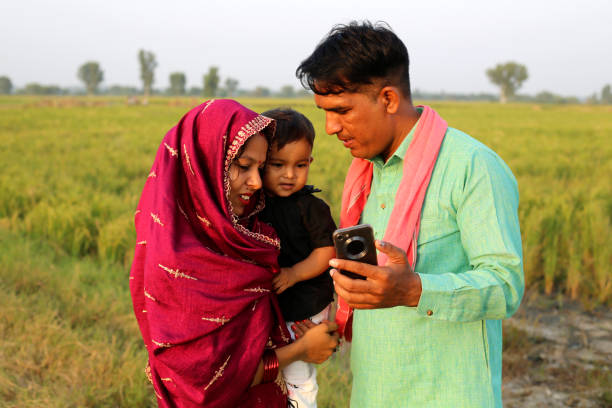 istock Indian family using mobile phone near green field 1740997055