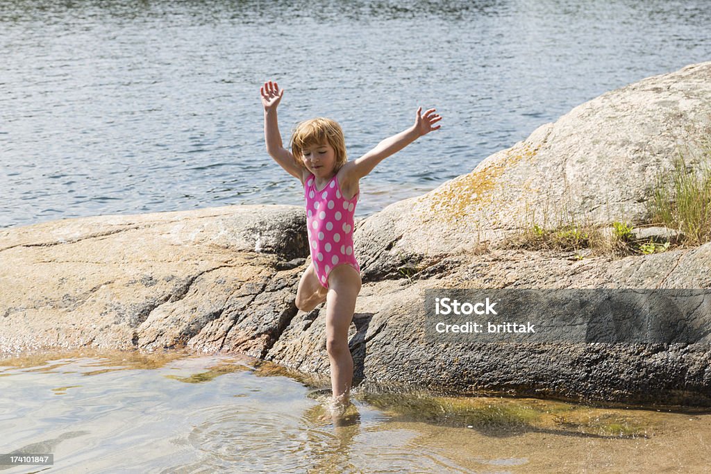 Little blond girl jumping into the sea from a cliff Little blond girl jumping into the sea from a cliff in Stockholm Aerchipelago. 4-5 Years Stock Photo