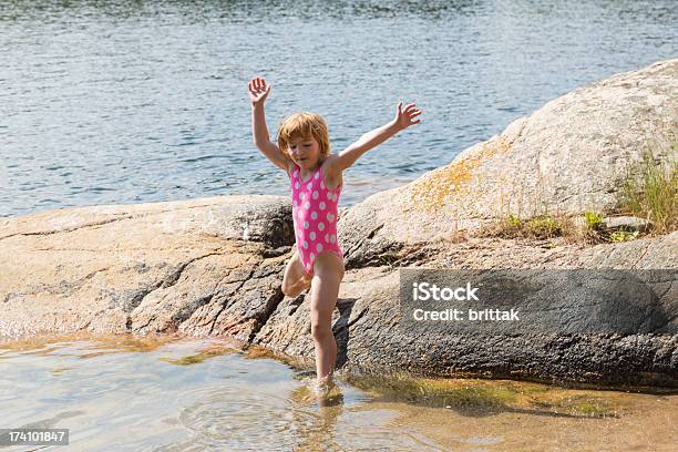 Little Blond Girl Jumping Into The Sea From A Cliff Stock Photo - Download Image Now
