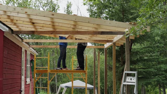 Time Lapse of a couple building a wooden roof for their cabin deck