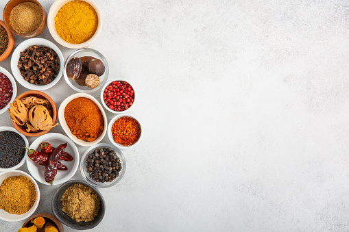 Assorted colorful spices in small bowls on gray background. Food background. Top view, copy space.