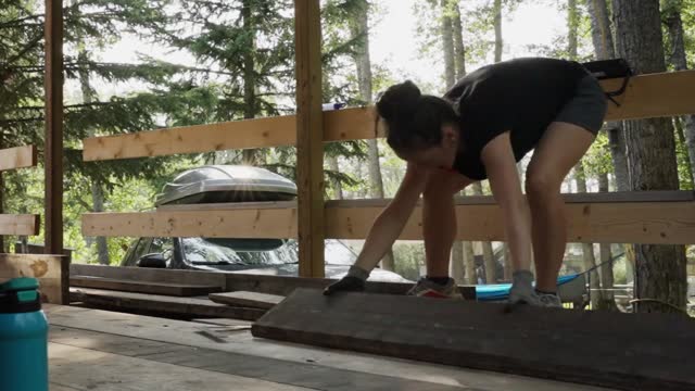Time lapse of a couple laying planks down on a deck frame