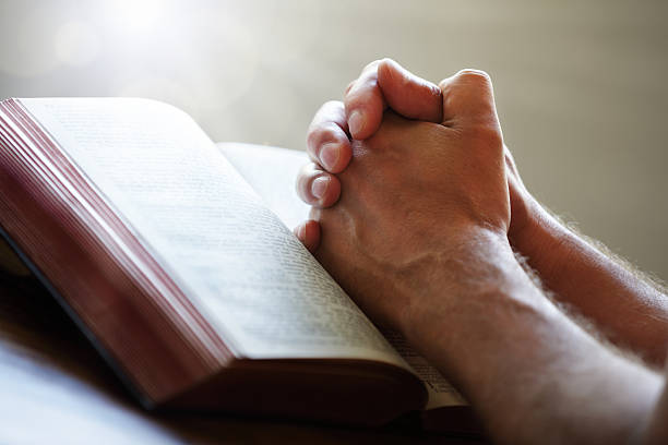 istock Hands praying on top of a Bible 174104739