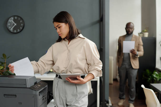 istock Young serious businesswoman with tablet taking printed paper document 1741050721