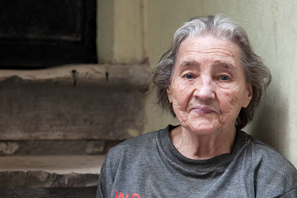 Elderly woman sitting on steps in a run down area Old woman in poverty sitting on street homelessness stock pictures, royalty-free photos & images