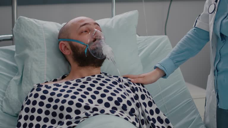 Patient sitting in bed while woman doctor puts oxygen mask