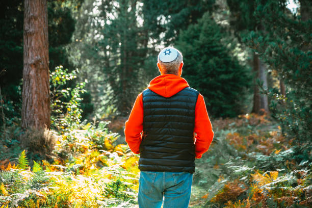 Jewish man wearing yarmulke walking on forest path