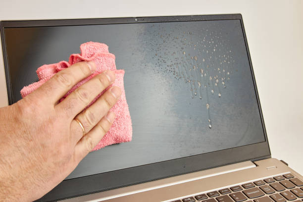 istock Man washes laptop display with detergent and rag. PC care concept 1741105069