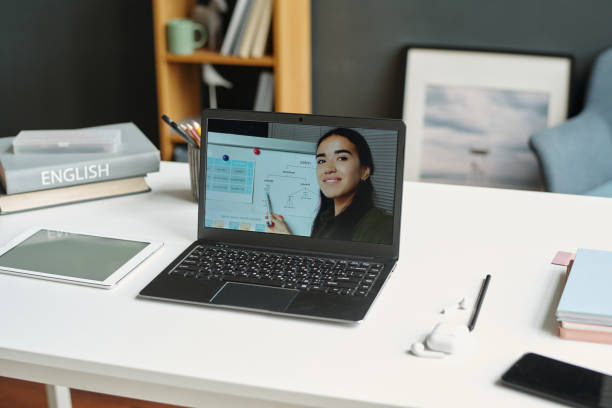 istock Laptop with English teacher on screen standing on desk with tablet 1741109403