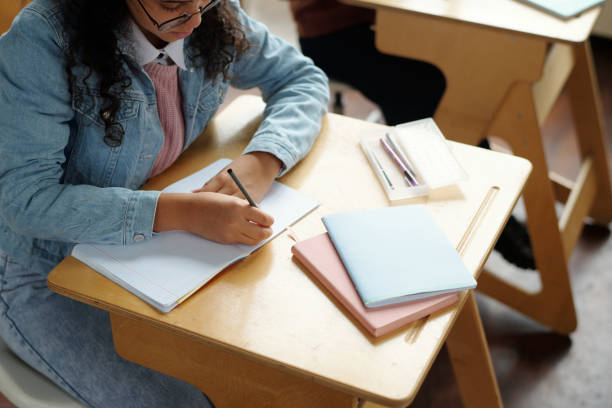 istock Above angle of diligent multiethnic schoolgirl making notes on page of copybook 1741110955