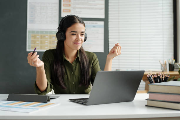 istock Confident young teacher in headphones explaining grammar rule to online learner 1741110984
