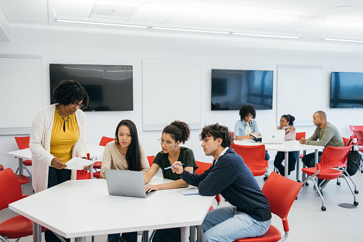 Teacher assisting University Students in Classroom