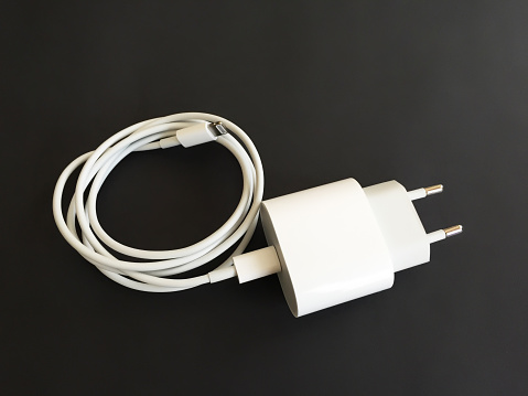 Mobile phone charger. Smart phone charging cable and electric plug on black background