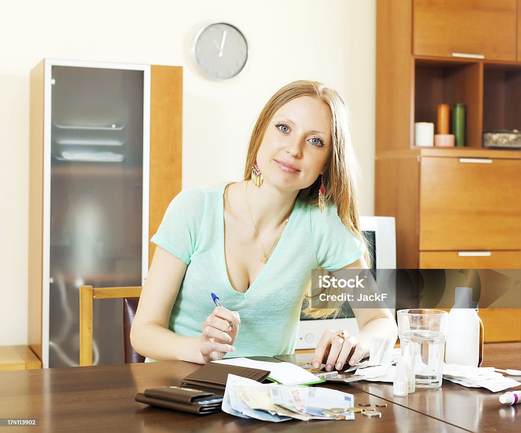 Long-haired blonde woman with medications and money Long-haired blonde woman with medications and money at table in living room Adult Stock Photo