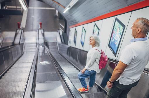 Husband and wife riding on escalator in subway station in Vienna together.