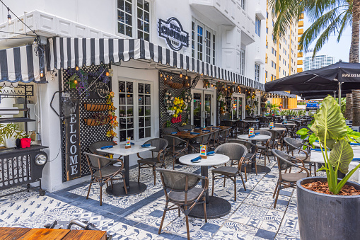 Miami Beach, Florida, USA - August 31, 2022: View of Ocean Drive and its famous sidewalk hospitality businesses, along South Beach Miami in the historic Art Deco District. South Beach has been a prominent tourist destination for many years.