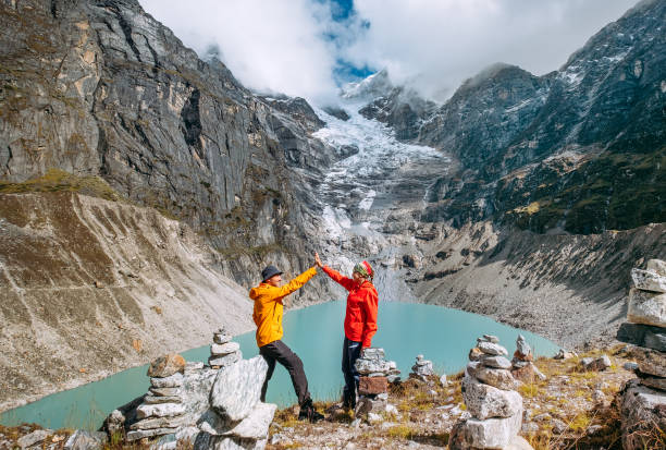 istock Trekkers couple dressed bright waterproof jackets giving High Five enjoying glacier falling in high altitude Sabai Tso glacial lake 4350m. Makalu Barun National Park, Mera peak climbing route, Nepal 1741161050