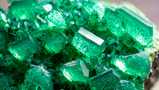 Glare sharp birthstone stack glisten depth fond of shiny vibrant dense irish mint malachite color lit by jade bio vert glow. Closeup view with space for text on ice refraction sparkle carbon ore heap