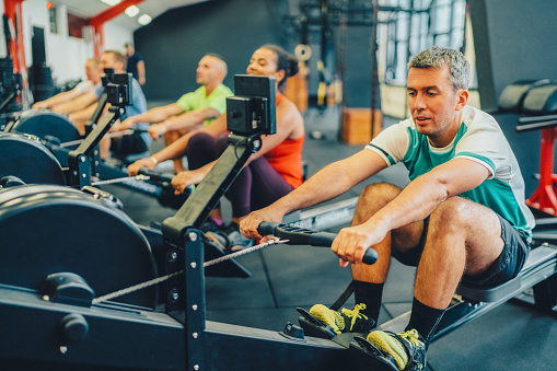 Group of people having rowing machine workout