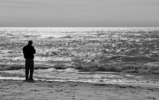 istock Man in silhouette standing at edge of ocean 174119626