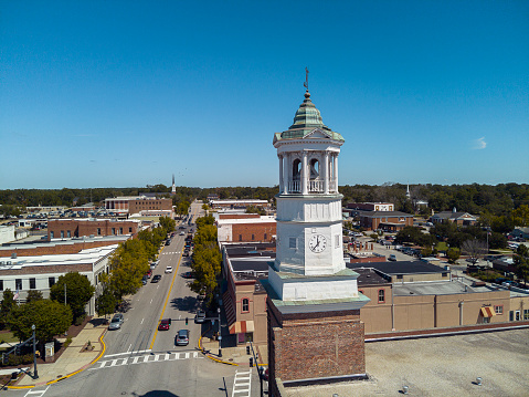 Clock Tower with vane stand on Broad Street in suburbs of Camden, SC. A water tower and church rise above the blue sky horizon. Aerial view